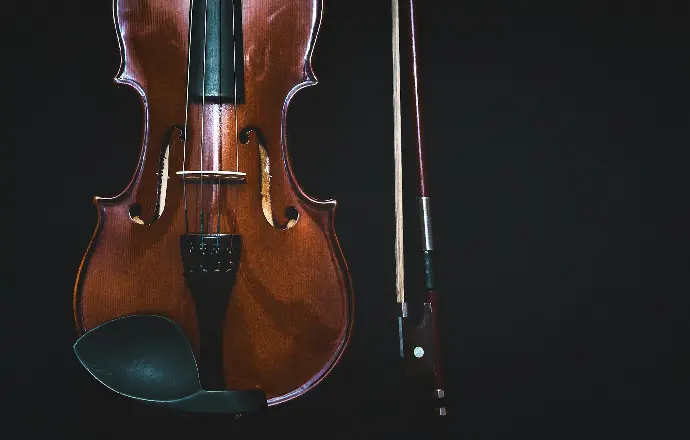 brown violin with bow in black background